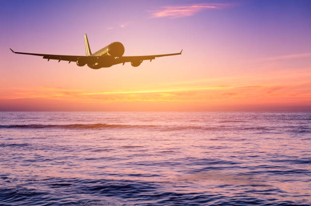 istock Airplane flying over tropical beach with smooth wave and sunset sky abstract background. Copy space of business summer vacation and travel adventure concept. Vintage tone filter effect color style. 1157475254