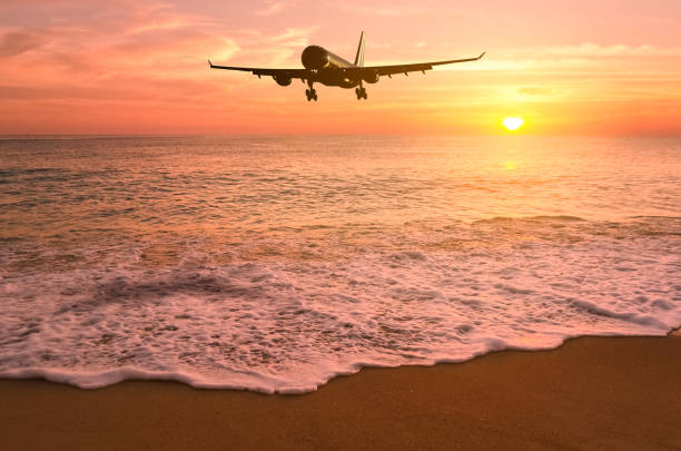 istock Airplane flying over tropical beach with smooth wave and sunset sky abstract background. Copy space of business summer vacation and travel adventure concept. Vintage tone filter effect color style. 1157475258