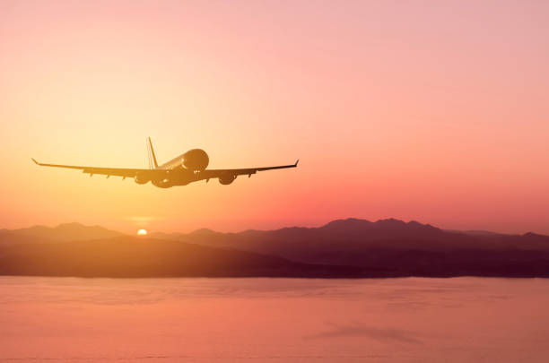 istock Airplane flying over tropical beach with smooth wave and sunset sky abstract background. Copy space of business summer vacation and travel adventure concept. Vintage tone filter effect color style. 1157475271