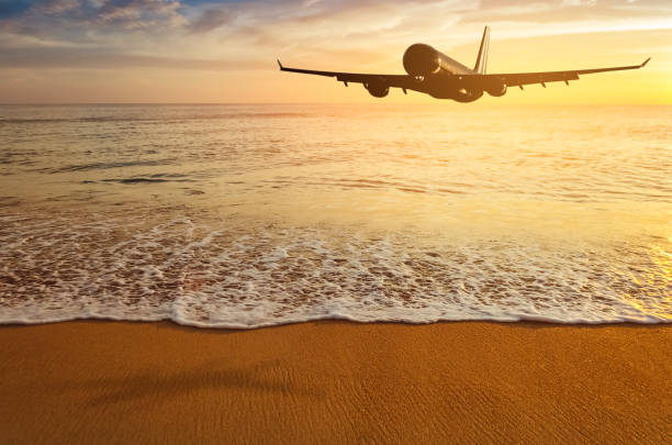 istock Airplane flying over tropical beach with smooth wave and sunset sky abstract background. Copy space of business summer vacation and travel adventure concept. Vintage tone filter effect color style. 1157475448