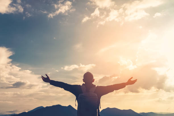 istock Backpacker man raise hand up on top of mountain with sunset sky and clouds abstract background. Copy space freedom travel adventure and feel good concept. Vintage tone filter effect color style. 1157476101