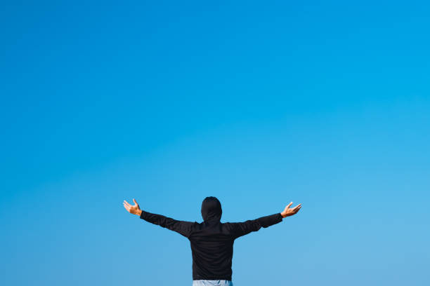 istock Copy space of man raise hands up on empty blue sky abstract background. Freedom feel good and summer vacation holiday concept. Vintage tone filter effect color style. 1157481105