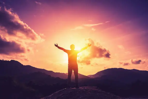 Photo of Copy space of man rise hand up on top of mountain and sunset sky abstract background. Freedom and travel adventure concept. Vintage tone filter effect color style.