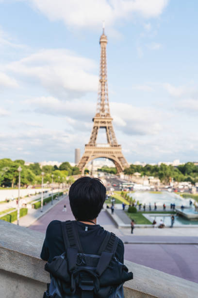 istock a man with backpack looking at Eiffel tower, famous landmark and travel destination in Paris, France. Traveling in Europe in summer 1157481211