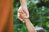 公園でお互いの手を握り合う母と娘