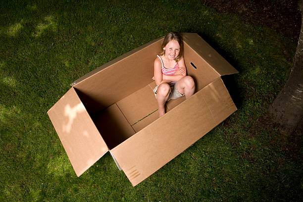 istock Young girl sitting in a cardboard box outside. 115748676