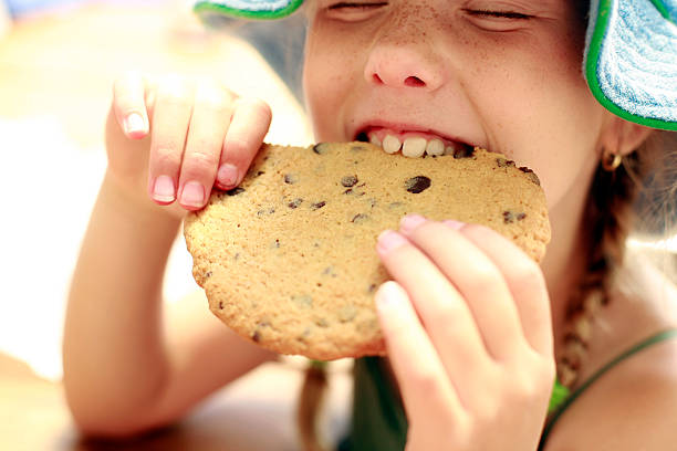 Little girl eating a big cookie.