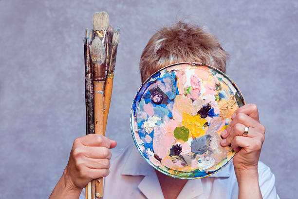 istock Artist holding brushes and paint pallet over face. 115748940