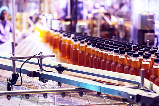 Industry, Business, Factory, Bottling Plant - Bottles Filled with Fresh Drink Moving on a Conveyor Belt to the Packaging Section of a Factory.