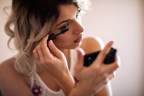 istock Beautiful young woman applying mascara 1157497201
