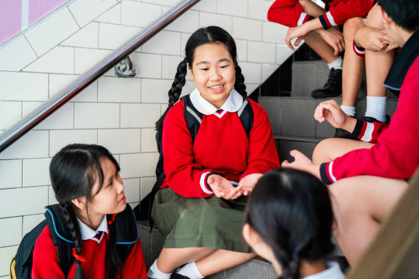 istock Smiling schoolgirl talking with friends on steps 1157498199