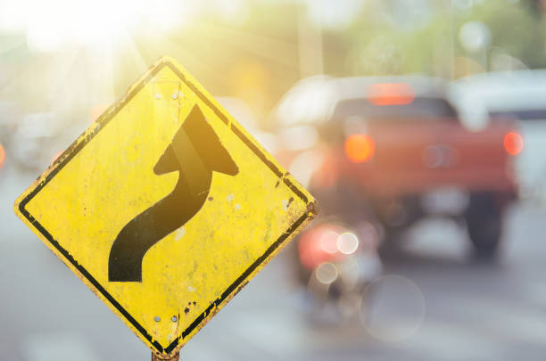 sinal de aviso velho da estrada da curva na estrada do tráfego do borrão com bokeh colorido fundo abstrato claro. copie o espaço do conceito do transporte e do curso. estilo retro da cor do filtro do tom. - avenue sign - fotografias e filmes do acervo