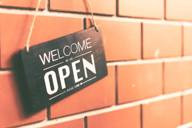 Photo of Open sign hanging on brown stone wall texture background. Business and service concept.