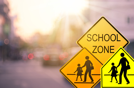 istock School zone warning sign on blur traffic road with colorful bokeh light abstract background. Copy space of transportation and travel concept. Vintage tone color style. 1157499287