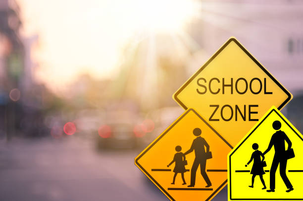 school zone warning sign on blur traffic road with colorful bokeh light abstract background. copy space of transportation and travel concept. vintage tone color style. - school imagens e fotografias de stock