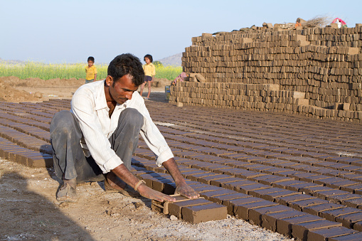 Dudani, India- January 11, 2013: indian rural man working on pile of bricks, each man making six hundred brick in 8 hour, January 11-2013,