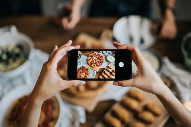 Woman's hand taking pictures of food on the table with smartphone during party with friends Woman's hand taking pictures of food on the table with smartphone during party with friends chinese ethnicity china restaurant eating stock pictures, royalty-free photos & images