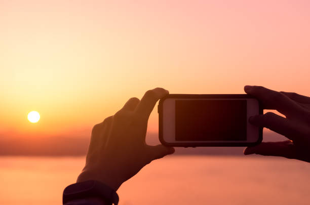 istock Silhouette man holding smart phone taking photo on tropical sunset beach background. Copy space travel vacation and business technology concept. 1157499996
