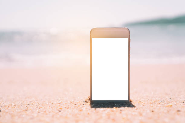 istock Smart phone on tropical sand beach with bokeh sun light wave texture background. Black copy space of technology and travel nature concept. 1157500027