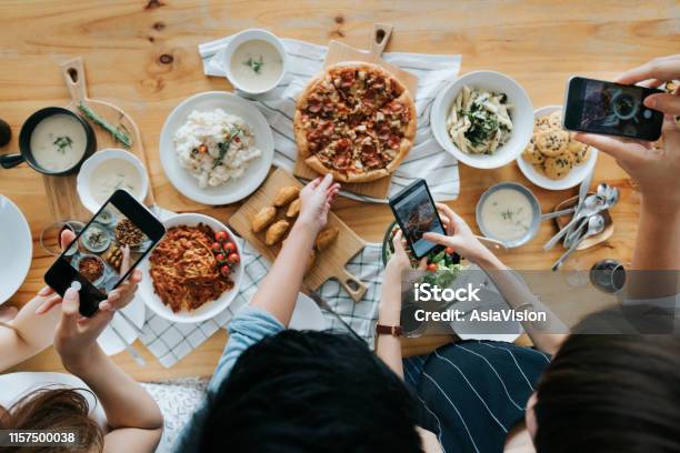 Group Of Friends Taking Pictures Of Food On The Table With Smartphones During Party Stock Photo - Download Image Now