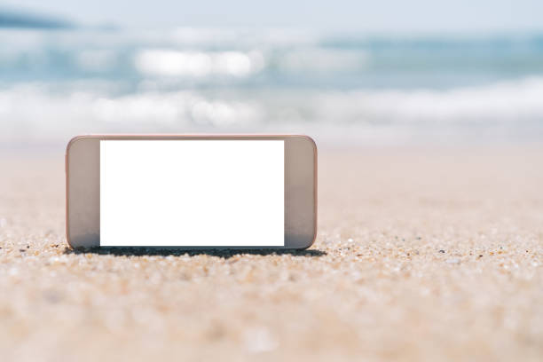 istock Smart phone on tropical sand beach with bokeh sun light wave texture background. Black copy space of technology and travel nature concept. 1157500053