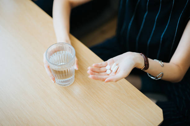 Close up of woman holding a glass of water and medication in her hand stock photo