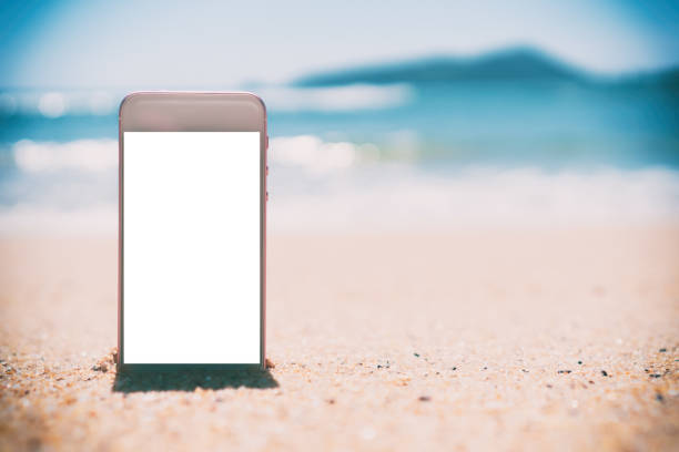 istock Smart phone on tropical sand beach with bokeh sun light wave texture background. Black copy space of technology and travel nature concept. 1157500178