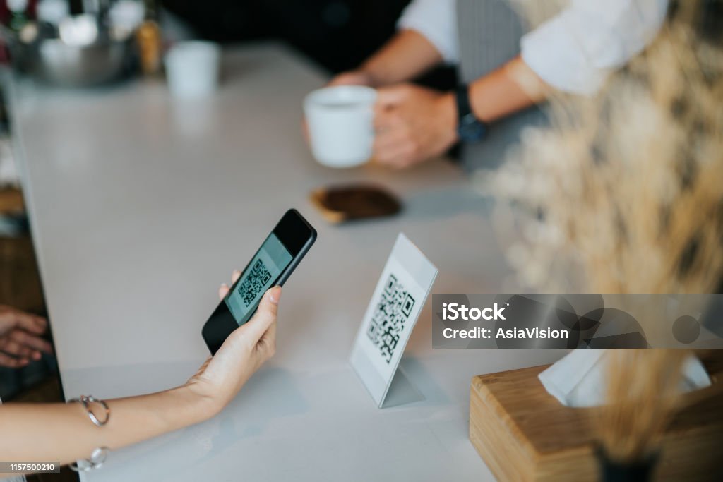 Woman's hand holding smartphone, scanning barcode for contactless payment in the cafe QR Code Stock Photo
