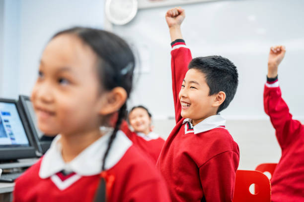 istock Happy boy sitting with hand raised amidst friends 1157500299