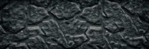 istock Black aged stone wall wide texture. Dark rough surface large background 1157500505