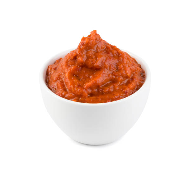 Ajvar or Pindjur Orange Vegetable Spread made from Bell Peppers Ajvar or pindjur orange vegetable spread made from bell peppers, eggplants and oil. Marinara sauce, salsa, chutney or lutenica in white bowl isolated with clipping path marinara stock pictures, royalty-free photos & images