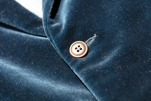 detail of a button on green corduroy pants