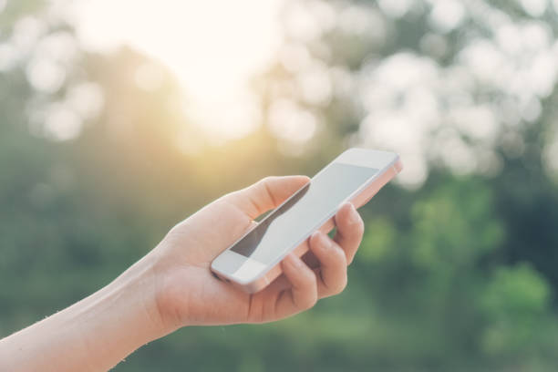 istock Woman hand using smart phone at outdoor nature park with sunset sky abstract background. Copy space technology business and travel nature holiday concept. Vintage tone filter effect color style. 1157504246
