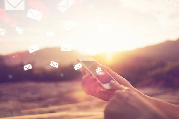 Woman hand using smart phone on top of mountain and sunset sky double exposure with icon email flying and colorful bokeh light abstract background. Technology business and travel concept. Vintage tone