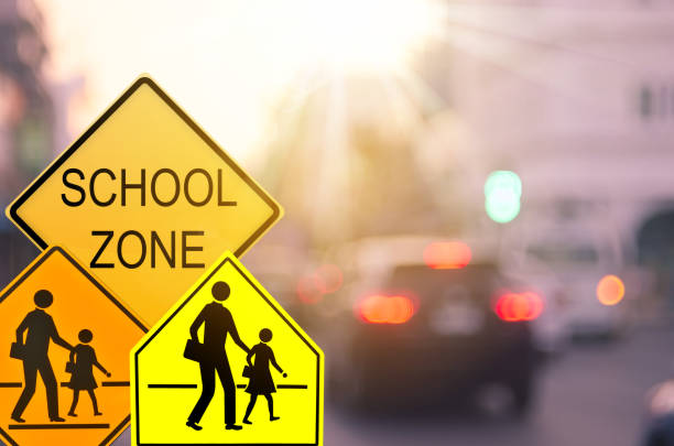 School zone warning sign on blur traffic road with colorful bokeh light abstract background. Copy space of transportation and travel concept. Vintage tone color style. School zone warning sign on blur traffic road with colorful bokeh light abstract background. Copy space of transportation and travel concept. Vintage tone color style. time zone stock pictures, royalty-free photos & images