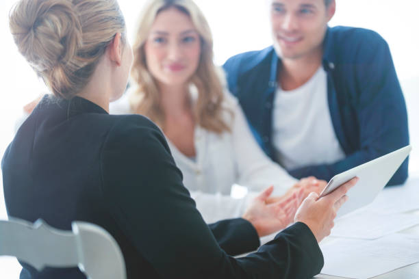istock Real estate agent with couple looking through documents. 1157507695