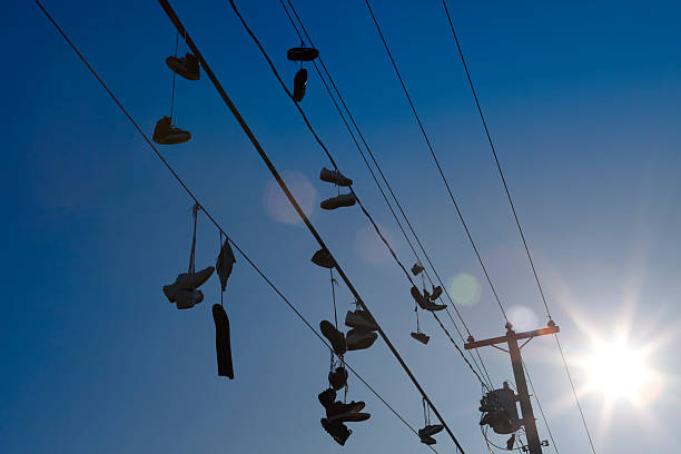 boots hang on wires against the background of the blue sky