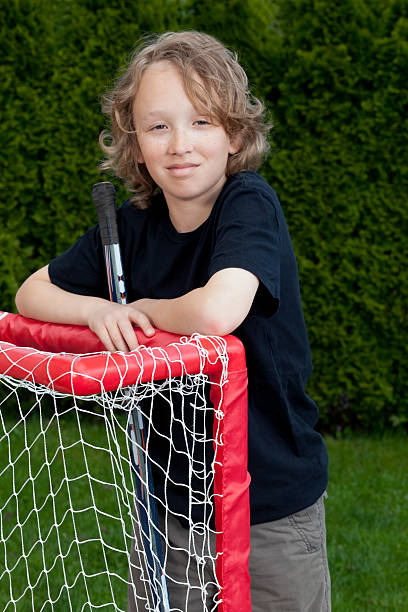 istock Pre teen boy standing outside leaning on roller hockey net. 115751207