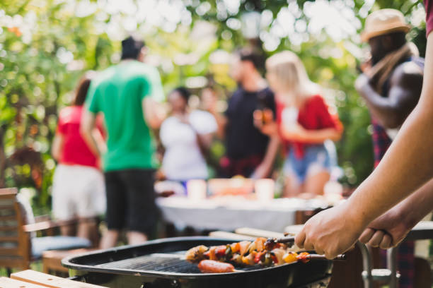 gruppo di persone che hanno una festa barbecue / barbecue a casa, cucinano carne / manzo alla griglia per pranzo, concetto di stile di vita della festa degli amici felici - barbecue foto e immagini stock