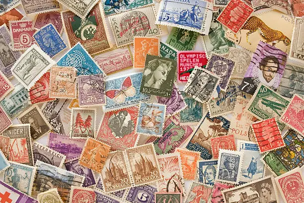 Colorful collection of old stamps spread out and overlapping on a flat surface.