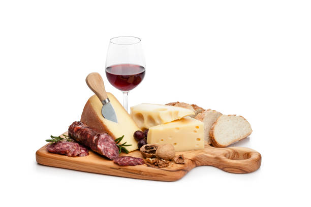 Cheese and wine platter isolated on white background Cheese and wine: cutting board with cheese slices, spanish chorizo, grape and walnuts isolated on white background. A red wine bottle and a wineglass are behind the cheese tray. Useful copy space available for text and/or logo. High key DSRL studio photo taken with Canon EOS 5D Mk II and Canon EF 100mm f/2.8L Macro IS USM. cheese wine food appetizer stock pictures, royalty-free photos & images