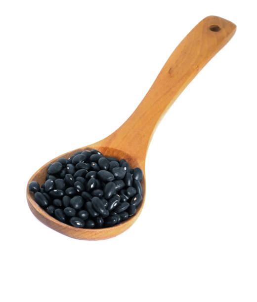 istock black beans with wooden spoon on white background 1157516982