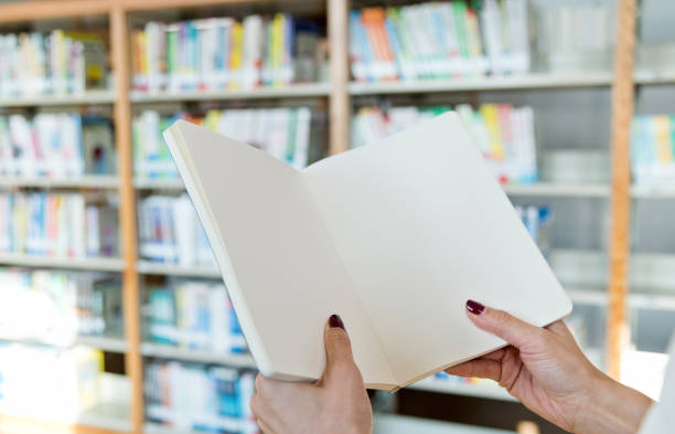 istock Woman hand holding a blank book in the library 1157517892