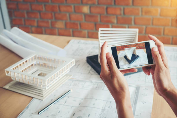 istock Architect using smart phone photograph model building in office 1157527126