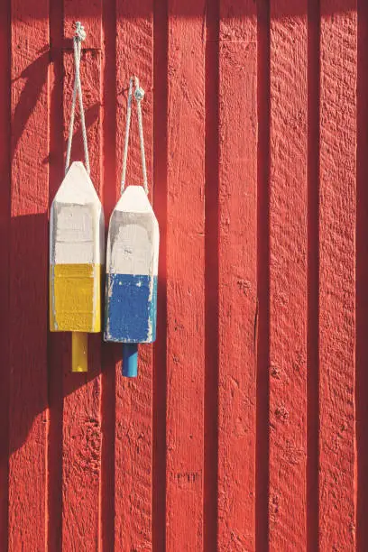 Photo of Fishing buoys on red wooden wall, vertical