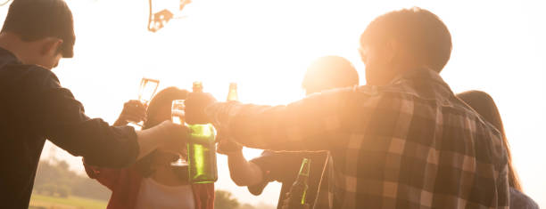 Hands of man in group of friends opening champagne for celebrate, cropped dimension for banner stock photo