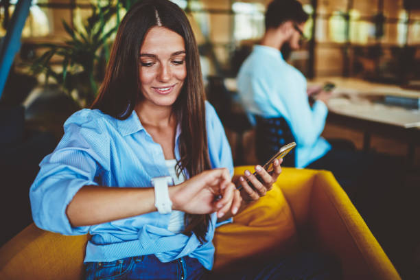 Positive smiling hipster girl checking notification and gps tracking on electronic smartwatch, happy successful woman holding modern smartphone device in hand while looking on wearable wristwatch positiva smiling hipster chica comprobación notificación y seguimiento gps en el reloj inteligente electrónico, feliz mujer exitosa sosteniendo el dispositivo moderno del teléfono inteligente en la mano mientras mira en el reloj de pulsera portátil