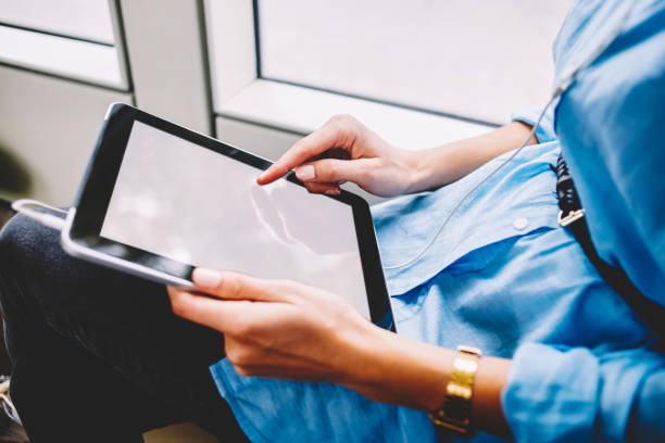 istock Cropped image of woman using modern digital tablet with mock up screen in public transport with wifi access, female  tap on blank portable pc checking new feed in social networks inside bus 1157541468
