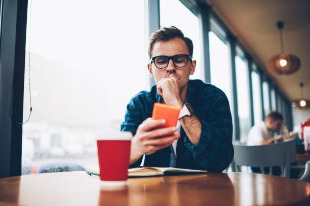 istock Handsome pensive smart male student dressed in trendy outfit texting email message using application on smartphone.Good looking man solving banking issue chatting with online support via cellphone 1157541974