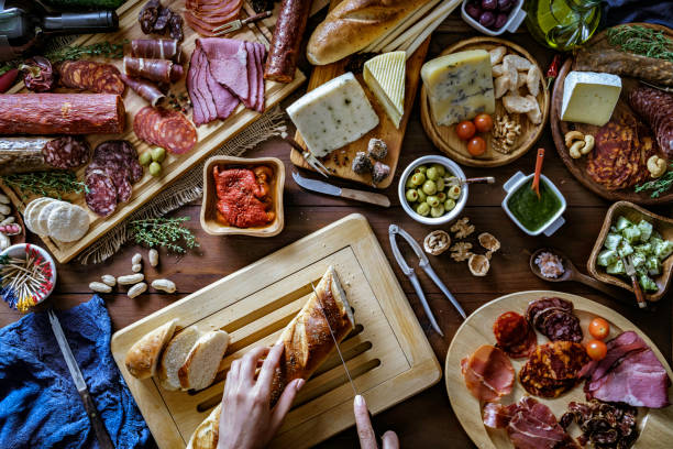 istock Female hands preparing snacks and appetizers in a set full of assorted Cured ham and cheese on rustic wood 1157543970